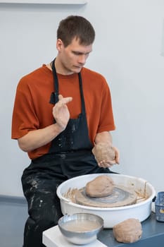 A potter kneads clay before using it on the potter's wheel. Vertical photo