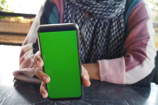 Person holding a smartphone with a green screen for customized content. Screen is ready for personalized information