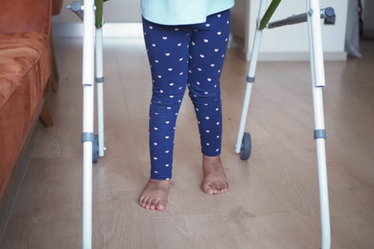 child with walking frame and knee orthosis indoor .