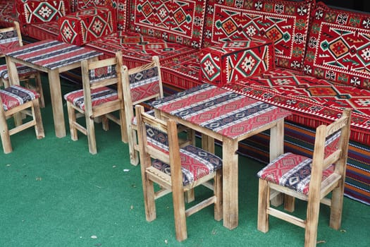 Outdoor seating at a traditional cafe featuring patterned cushions and rustic wooden tables and chairs.