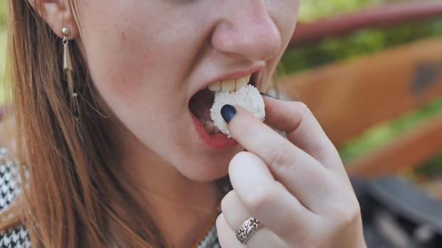 The girl is eating round white coconut candy