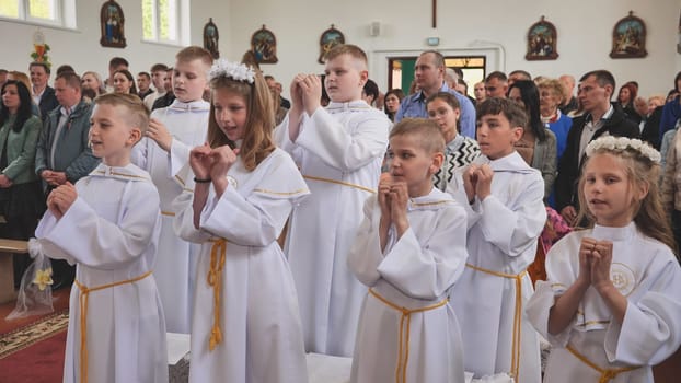 Children sing at their First Catholic Communion.