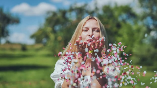 A girl blows a multi-coloured paper confetti out of her hands