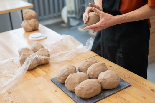 A potter kneads clay before using it in the workshop. Close-up of a man's hands