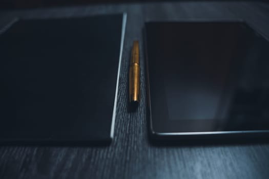 Workplace. Notebook with pen and tablet on a wooden table. Strict style. High quality photo