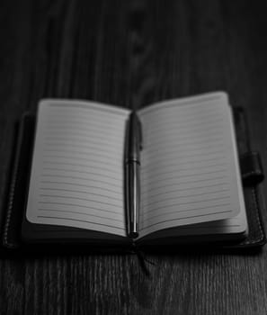 Black and White photo - Notepad with pen on a wooden table. Business, finance and creativity. Workplace. High quality photo