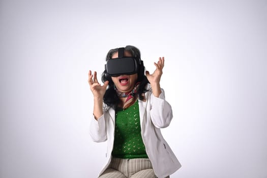 Amazed senior woman VR headset enjoying virtual reality experience isolated on white background.