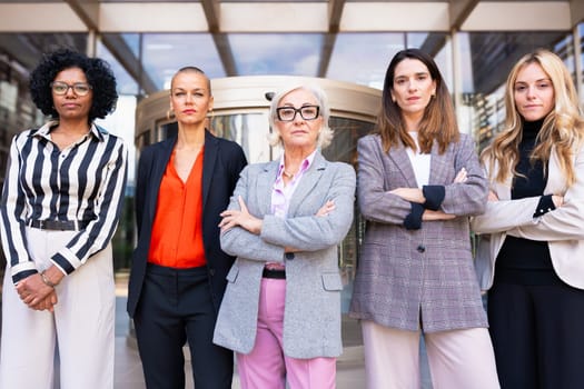 Five businesswomen standing side by side with their arms crossed looking at the camera serious. Suitable for team, friendship and diversity concepts.