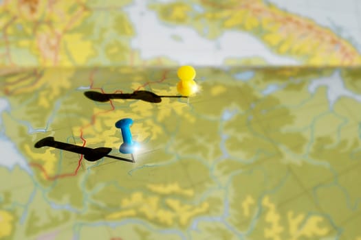 Yellow and blue pushpin showing the location of a destination point on a map. travel concept