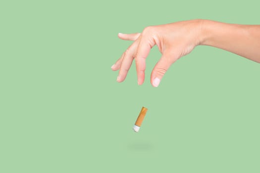 female hand throwing a cigarette on isolated green background.