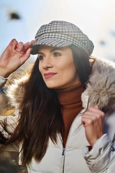 Beautiful young brunette woman in jacket poses on meadow on sunny day