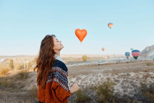 Woman admiring hot air balloons in cappadocia with heart shaped balloon in hand