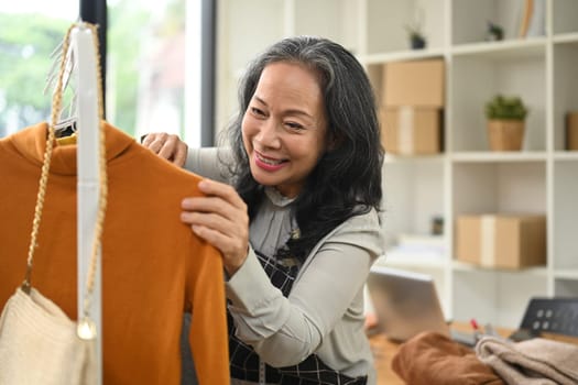 Cheerful middle age small business owner working in her clothing store.