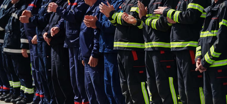 A group of firefighters lined up, saluting the flag, applauding in solidarity, and gearing up for intensive training sessions, showcasing their unwavering commitment to service and teamwork