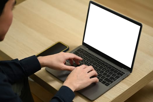 Cropped shot of young man sitting on couch and using laptop working remotely at home.