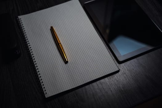 Workplace. Notebook with pen and tablet on a wooden table. Strict style. High quality photo