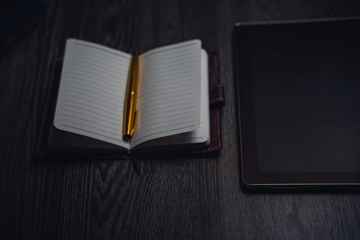 Workplace. Notebook with pen and tablet on a wooden table. Strict style. High quality photo