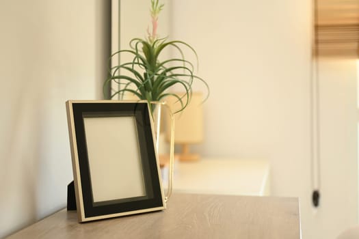 Empty photo frame on the wooden table in the living room.