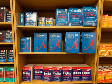 Multi-colored dictionaries and grammars of French and English are on the shelves in the store. High quality photo