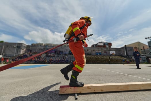 In a dynamic display of synchronized teamwork, firefighters hustle to carry, connect, and deploy firefighting hoses with precision, showcasing their intensive training and readiness for challenging and high-risk situations ahead.