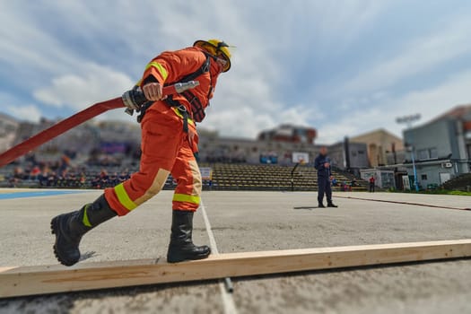 In a dynamic display of synchronized teamwork, firefighters hustle to carry, connect, and deploy firefighting hoses with precision, showcasing their intensive training and readiness for challenging and high-risk situations ahead.