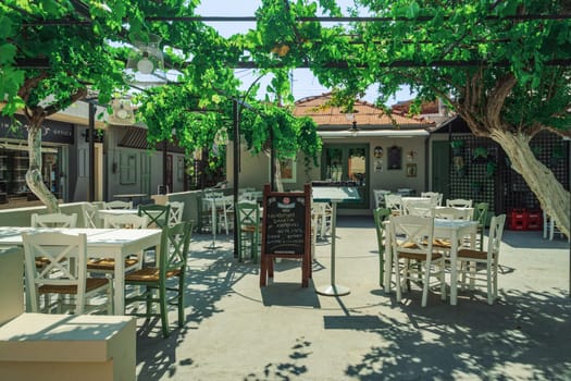 Kefalonia, Greece - July 8 2021: Ionian Island empty tavern with outdoor seating area with wooden chairs and tables.