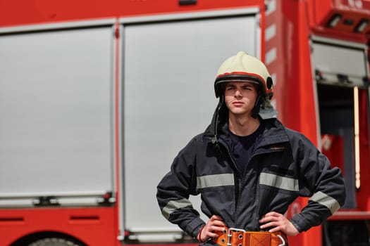 A firefighter, adorned in professional gear, stands confidently beside a fire truck following a grueling firefighting training session