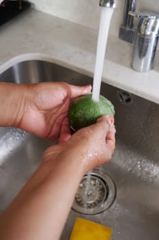 hand washing avocado with water sprinkling.