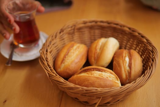 bread rolls rest in a black bowl on the table.