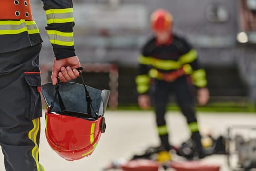 A close up shot capturing the hand of a firefighter holding a fire helmet with a strong sense of readiness and determination.