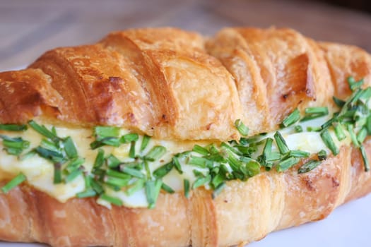 Tasty croissant sandwich filled with fresh herbs and creamy filling, perfect for breakfast or brunch.