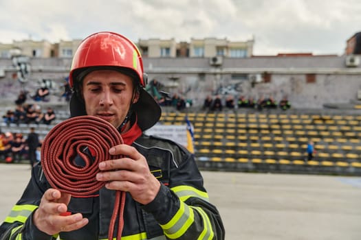 A dedicated firefighter meticulously coils the fire hose after successfully extinguishing a blaze, showcasing the critical post-incident responsibilities.