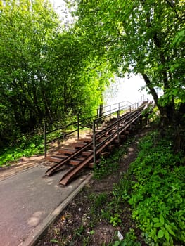 Stairs among the green trees to the summer park. Pedestrian passage. High quality photo