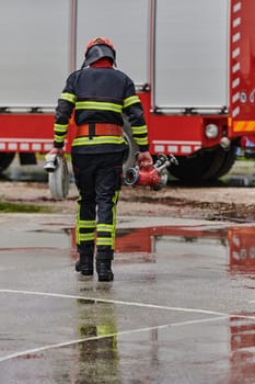 In a dynamic display of synchronized teamwork, firefighters hustle to carry, connect, and deploy firefighting hoses with precision, showcasing their intensive training and readiness for challenging and high-risk situations ahead.