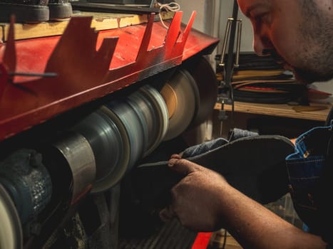 shoemaker shaping the sole of a shoe on the polishing machine