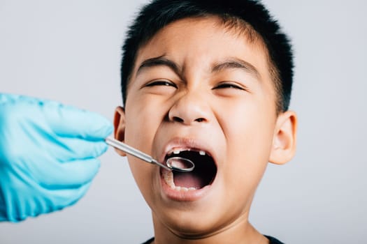 After removing a child's loose milk tooth a pediatric dentist conducts an examination. Dental tools assist in thorough check-up at dental office. Doctor uses mouth mirror to checking teeth cavity