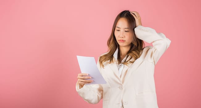 Portrait of beautiful Asian young woman sad tired strain holding paper calculating bills on hand, female person problem she hold worried over bill, studio shot isolated on pink background