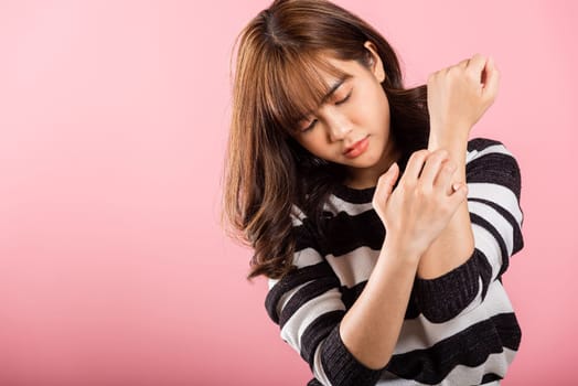 Asian beautiful woman itching her scratching her itchy arm on pink background with copy space, Medical and Healthcare concept, female skin problems scratch the itch with her arm