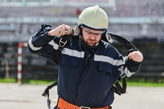 A firefighter dons the essential components of their professional gear, embodying resilience, commitment, and readiness as they gear up for a hazardous firefighting mission, a testament to their unwavering dedication to protecting and saving lives.