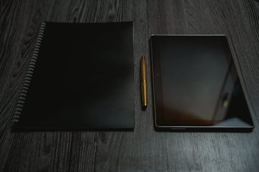 Workplace. Notebook with pen and tablet on a wooden table. Strict style. High quality photo