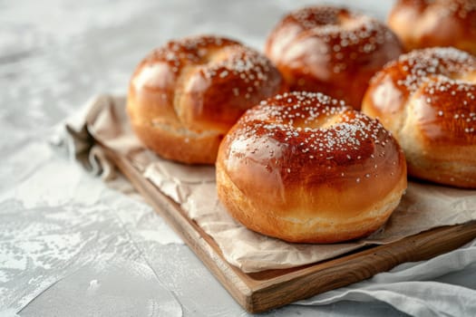 A plate of cinnamon rolls with powdered sugar sprinkled on top. The rolls are arranged on a wooden cutting board with a few sprigs of rosemary nearby