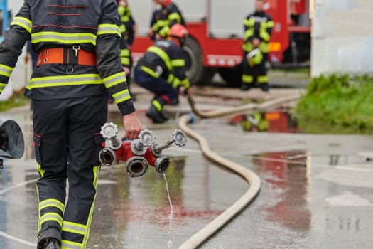 In a dynamic display of synchronized teamwork, firefighters hustle to carry, connect, and deploy firefighting hoses with precision, showcasing their intensive training and readiness for challenging and high-risk situations ahead.