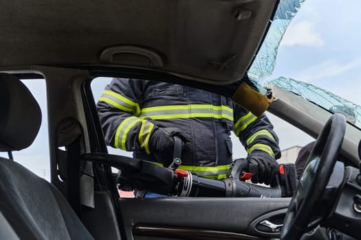 A dedicated team of professional firefighters employs specialized tools to cut and break through vehicle wreckage, showcasing their skilled collaboration and swift response in rescuing individuals involved in a car accident.