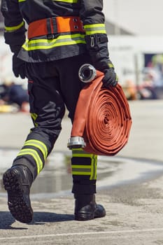 In a dynamic display of synchronized teamwork, firefighters hustle to carry, connect, and deploy firefighting hoses with precision, showcasing their intensive training and readiness for challenging and high-risk situations ahead.