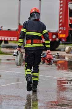 In a dynamic display of synchronized teamwork, firefighters hustle to carry, connect, and deploy firefighting hoses with precision, showcasing their intensive training and readiness for challenging and high-risk situations ahead.