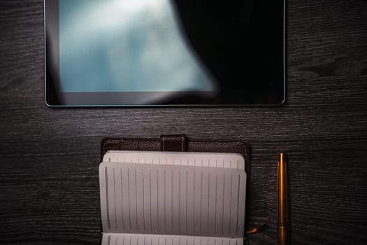 Workplace. Notebook with pen and tablet on a wooden table. Strict style. High quality photo