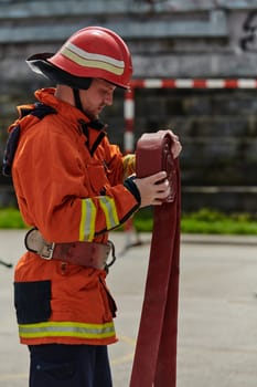 A dedicated firefighter meticulously coils the fire hose after successfully extinguishing a blaze, showcasing the critical post-incident responsibilities.