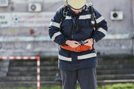 A firefighter dons the essential components of their professional gear, embodying resilience, commitment, and readiness as they gear up for a hazardous firefighting mission, a testament to their unwavering dedication to protecting and saving lives.