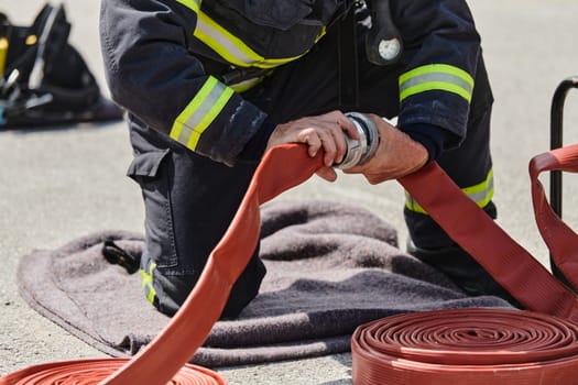 A dedicated firefighter meticulously coils the fire hose after successfully extinguishing a blaze, showcasing the critical post-incident responsibilities.