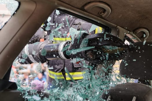 A dedicated team of professional firefighters employs specialized tools to cut and break through vehicle wreckage, showcasing their skilled collaboration and swift response in rescuing individuals involved in a car accident.